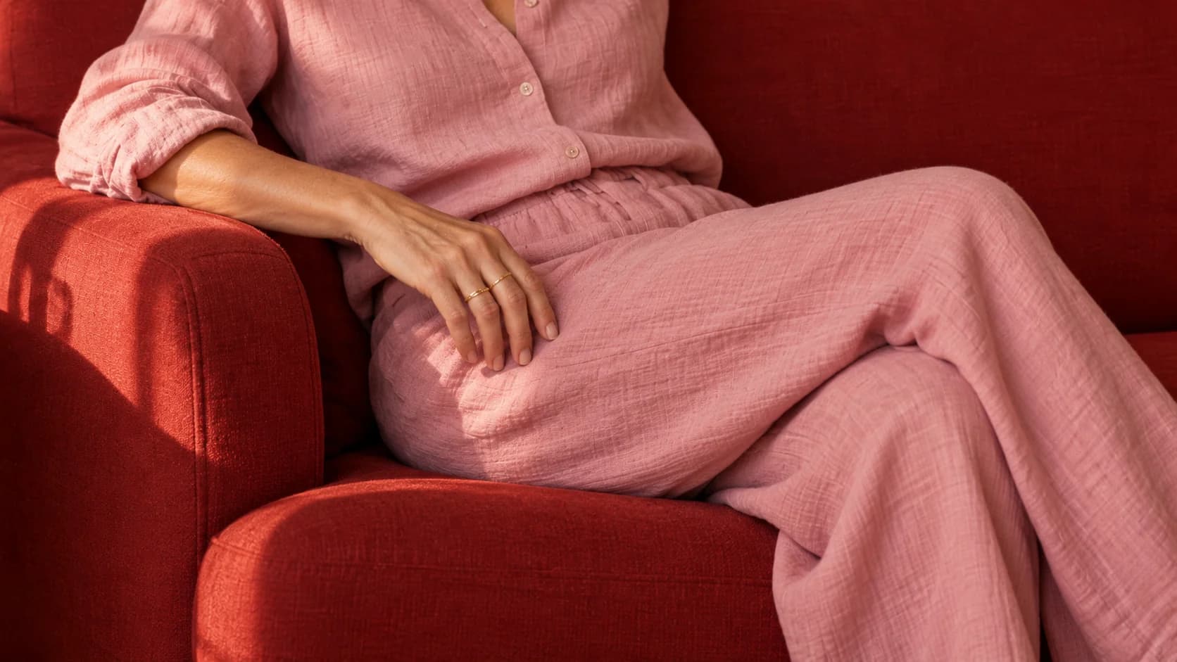A hand resting on pink linen in sunlight.